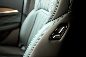 Car seat adjustment control, in interior of a car, with car seat, adjustment lever, with plastic, textile texture, from a close-up perspective, with black, gray accents. © Евгений Вершинин