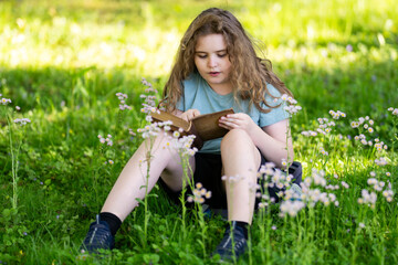 Fototapeta premium Focused expression shows serious reading. Young focused girl studies quietly. Focused kid reads in blurred bokeh. Focused learning creates educational portrait.