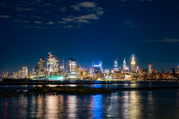Obraz premium Hudson Yards towers at night. NYC, New York city at night. Modern Hudson Yards skyline district. Illuminated Hudson Yards waterfront reflection. Hudson Yards towers define Midtown.
