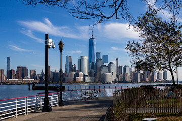 Fototapeta premium New York City waterfront with reflection. New York skyscraper skyline in daytime. New York urban panorama near harbor. NYC famous skyline with blue sky.