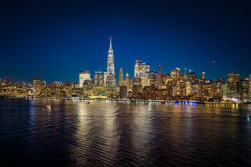 Obraz premium New York cityscape under storm sky. New York buildings shine in evening. New York City skyline with Manhattan. NYC waterfront panorama at twilight.