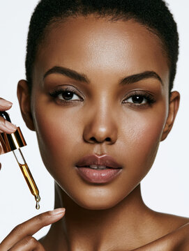 beautiful black african american woman applying cosmetic serum oil with a dropper closeup face of young female with perfect clean skin health care cosmetology dermatological treatment copy space
