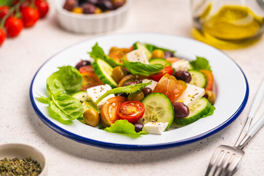 Greek salad of fresh cucumber, tomato, sweet pepper, lettuce, feta cheese and olives with olive oil on a white background. Healthy food. High quality photo