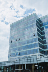 Obraz premium Workers clean windows on a tall office building in a city under a cloudy sky during daytime