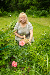 Serene senior woman looking at pink spiraea flower in the garden, cottagecore lifestyle profile portrait © Светлана Высокос