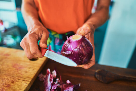 Woman peeling a red onion with a knife - home cooking close-up