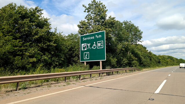 Services roadside sign on highway, green traffic information board with petrol station food and wc icons, motorway rest stop distance marker in UK