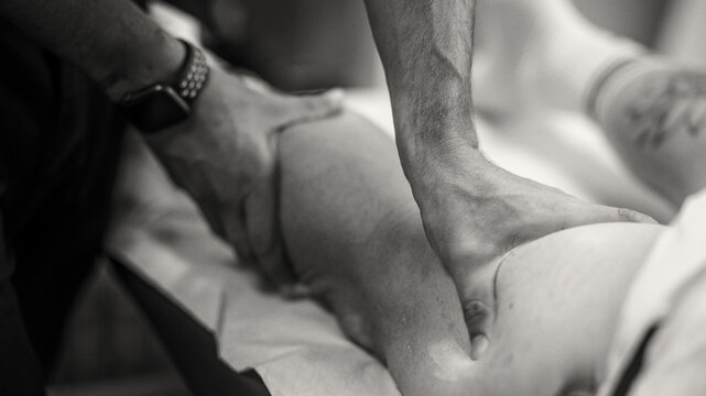Physiotherapist treats a muscle tear in a patient's leg on the couch in a clinical study