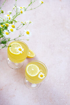 Traditional Italian limoncello or lemon liqueur. Outdoor table setting with flowers, with lemon slice, daisy flower, glass of lemonade, lemon halves, with glass, lemon texture, from a top-down