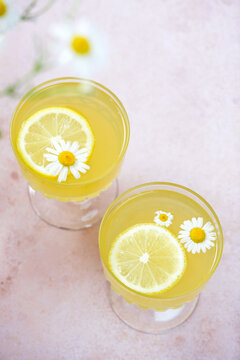 Traditional Italian limoncello or lemon liqueur. Outdoor table setting with flowers, with lemon slice, daisy flower, glass of lemonade, lemon halves, with glass, lemon texture, from a top-down