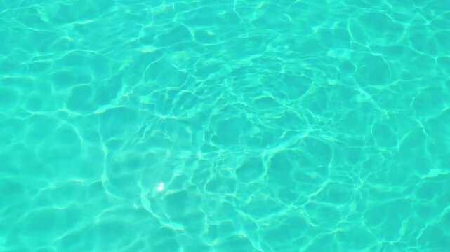 Clear turquoise swimming pool water with ripples and sunlight reflections surface blue light background wave