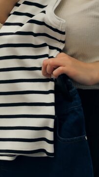 Female inspecting garment comfort and style today. Woman carefully scrutinizing fabric quality and overall clothing fit. Young woman thoroughly assessing comfort and design of her tank top today