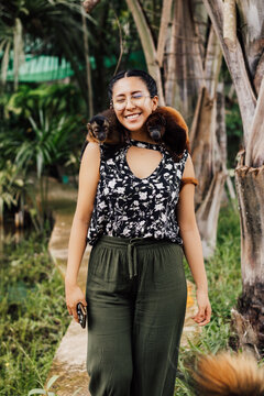 Mujer sonriente con los ojos cerrados sosteniendo dos peque&ntilde;os monos rescatados en sus hombros.