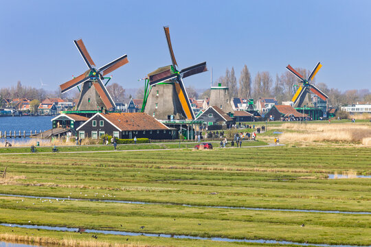 Zaandam, Netherlands, 22 March 2026. Tourists walking along the pathway next to traditional Dutch windmills at the historic Zaanse Schans village.