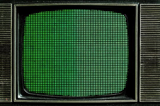 Close-up of an old television set with a green screen displaying a pixelated pattern