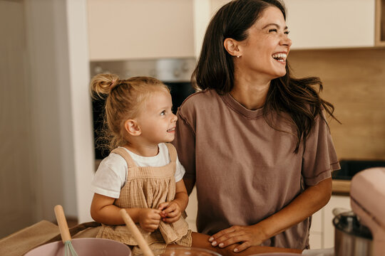 Mother and daughter baking, laughing, and bonding in kitchen