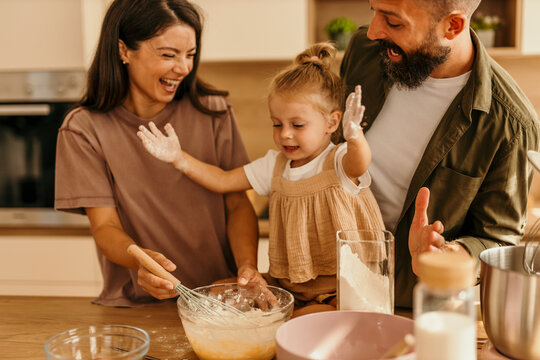 Happy family baking together in kitchen with flour