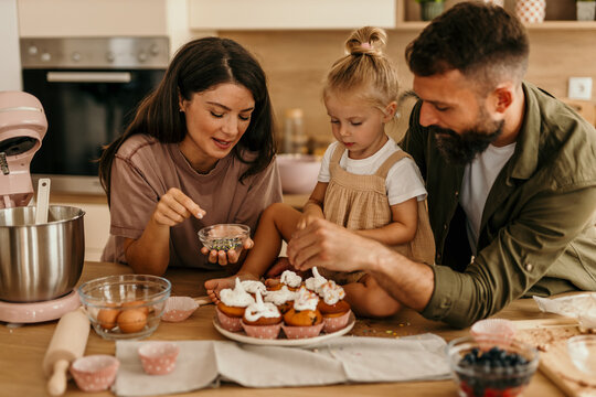 Family baking cupcakes together in modern kitchen
