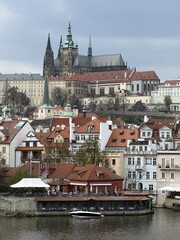 Obraz premium Panoramic View of Prague Castle and Historic Old Town Across the Vltava River, Czech Republic. Atmospheric European cityscape with medieval architecture and dramatic cloudy sky.