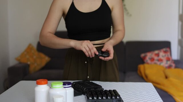 Health begins with small daily steps as woman organizes pills in weekly container at home highlighting routine care discipline and growing reliance on medication habits