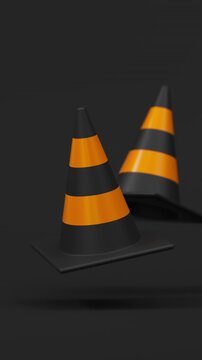 Front view pair of floating traffic cones in orange and black on a black background for road safety and construction warning. Vertical video.