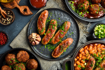 Fototapeta premium Grilled pork sausages with parsley, sauce and garlic. On a stone plate. Close-up.