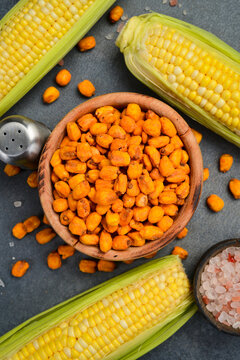 Fried salted corn kernels. On a dark background. Close-up.