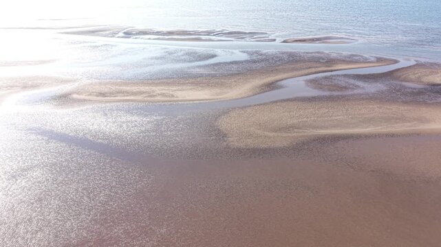 Aerial drone 4K footage showing the shoreline glowing under warm golden hour sunlight with soft reflections across the water Leasowe Wirral