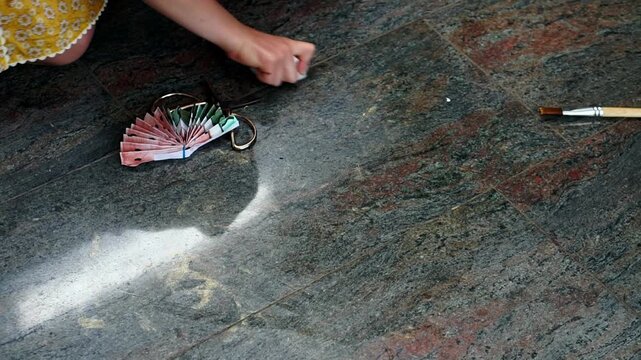 Top view of girl cleaning paint stains from floor after watercolor art session