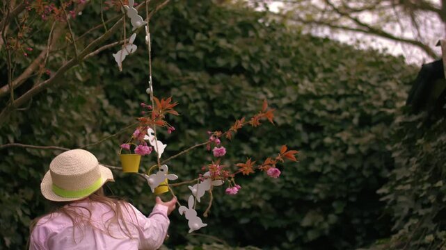 Woman wearing Easter bonnet and sits by easter decorations on blossom tree
