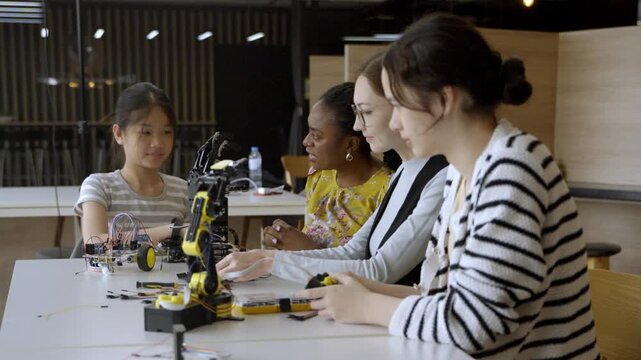 Students build robots in a classroom with teachers guiding them in a tech workshop