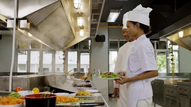 Cooking in a busy kitchen with two chefs preparing fresh meals during the lunchtime rush at a culinary school