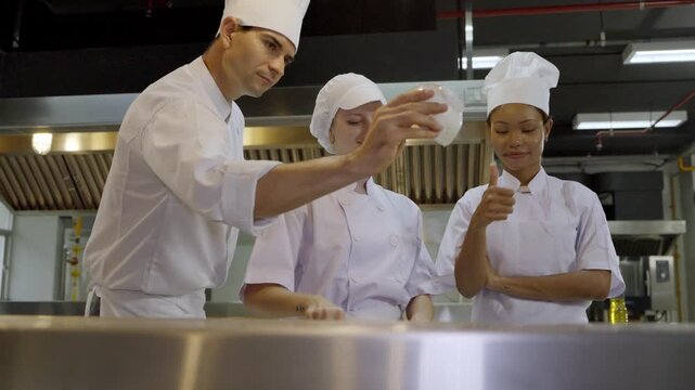 Cooks learning to prepare food in a kitchen while working together and sharing tips at a culinary school