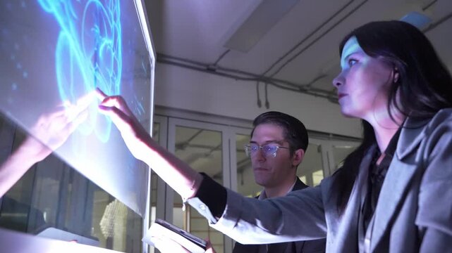 People discuss technology ideas in office setting during daytime with focus on digital screen showing graphics