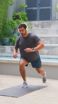 Vertical video: Stepping, man in shorts on pool mat with watch, alternating lunging for training