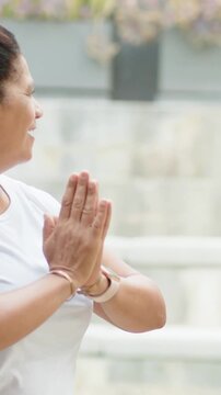 Vertical video: Starting hands near chest, woman pressing palms for calm on patio, band, copy space