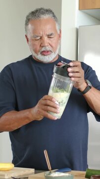 Vertical video: Checking man in dark shirt turning lid on blender cup in kitchen, preparing drink
