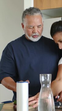Vertical video: Placing white cylinder, man in navy shirt guiding blender for prep at home counter