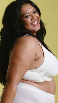 Vertical video: Smiling model posing and turning in studio, wearing white bra high waist underwear