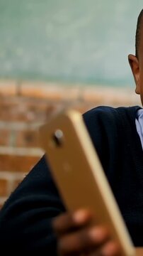 Vertical video: Holding gold phone, student wearing navy sweater reading screen, smiling at table