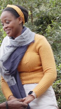 Vertical video: Reaching hand causing woman on bench holding hand in mustard knit, rosegold watch