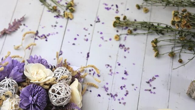 purple flowers, white flowers, floral arrangement, woven decorative balls, rattan balls, botanical decor, dried botanicals, dried flowers, scattered petals, purple petals, rustic wood background, weat