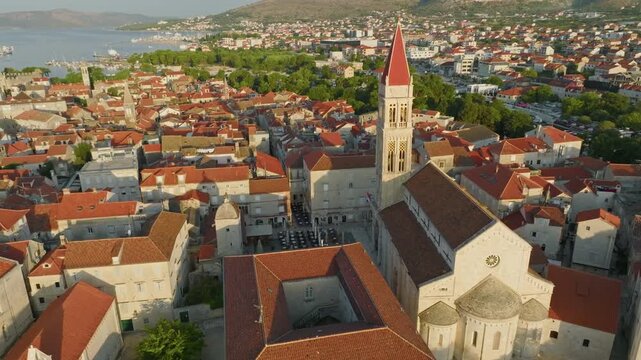 Aerial 4K of Cathedral of St Lawrence dominating historic old town of Trogir, Croatia. Traditional terracotta roofs and tall bell tower define ancient Mediterranean island of Trogir