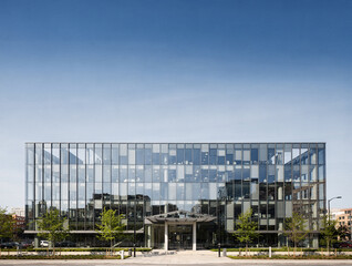Obraz premium A modern office building occupies the lower part of the scene. Clear skies above provide a bright backdrop. Surrounding green elements are visible on the ground