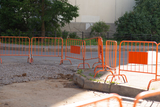 Temporary orange barriers around a sidewalk construction area outdoors, urban road repair, safety control, infrastructure work, city maintenance.