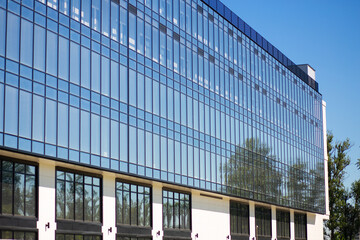Obraz premium Reflective glass office building exterior in a modern city, corporate architecture, business real estate, contemporary urban facade.