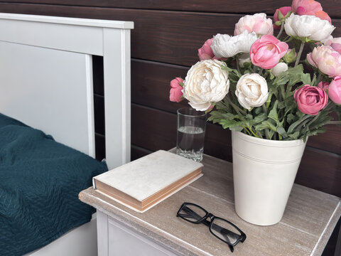 Pink and white flowers in a vase on a bedside table at home, cozy bedroom decor, romantic interior detail, calm lifestyle, fresh floral mood.