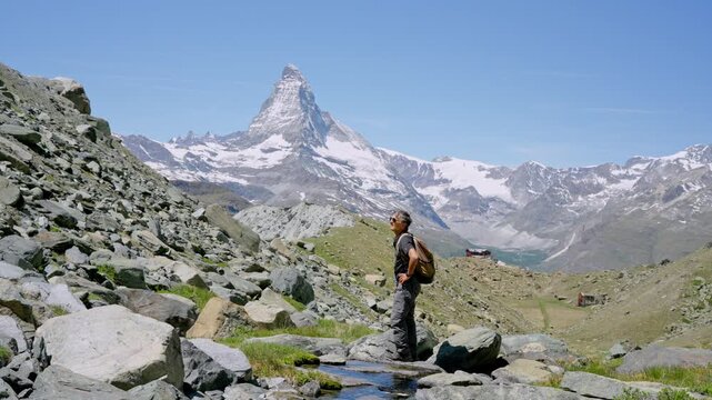 Senior man with a backpack hiking in the alps, admiring the majestic matterhorn peak in zermatt