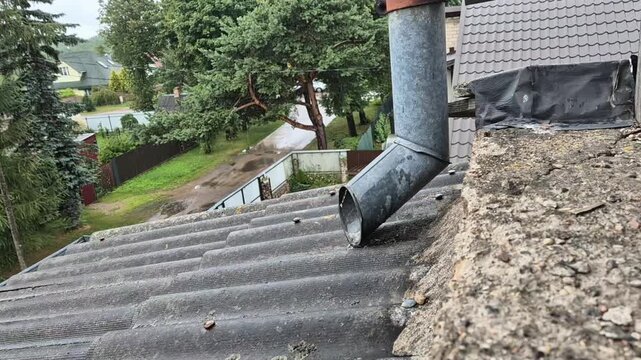 Close up view of heavy rain water flowing rapidly out of a roof downspout drainage pipe on a rainy day