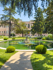 Obraz premium Ornate fountain surrounded by lush greenery and tranquil water reflections